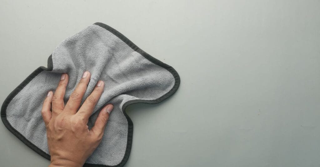Hand pressing a gray microfiber cloth flat on a surface
