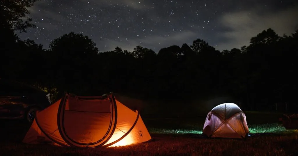 Two glowing tents under a starry night sky
