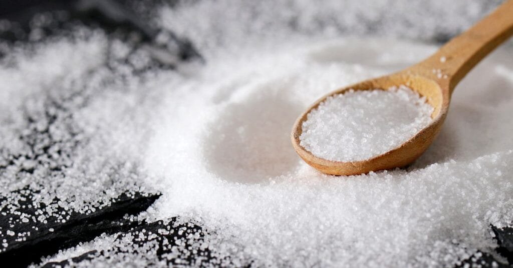 Fine white mineral litter granules piled with a spoon