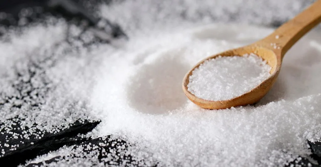 Fine white mineral litter granules piled with a spoon